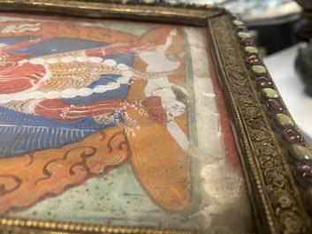 A Tibetan thangka in inlaid gilt brass frame, 19th C.